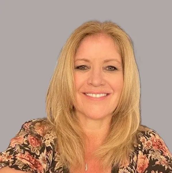 Woman smiling with blonde hair and floral top.