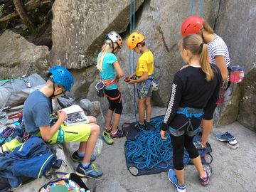 A group of kids preparing for rock climbing with helmets and harnesses.