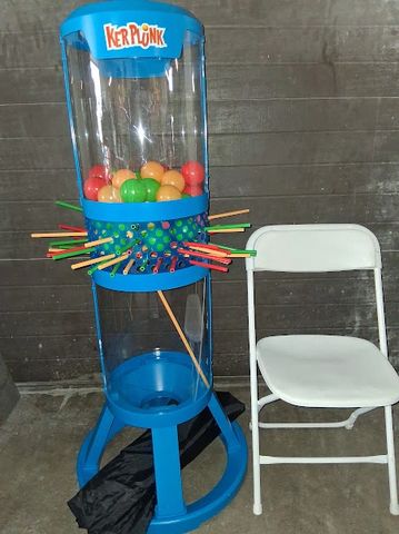 Blue Kerplunk game with colorful sticks and balls beside a white chair.