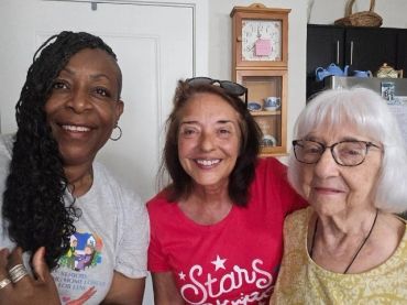 Three women smiling together indoors.