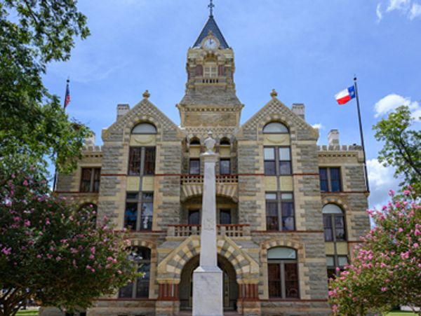Historic courthouse with clock tower and flags in Texas.