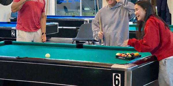 Three friends enjoying a game of pool together indoors.