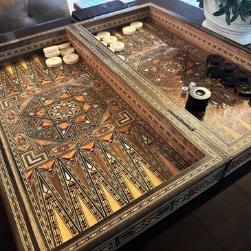 Intricately designed wooden backgammon board with black and white pieces and dice.