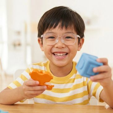 Smiling boy holding colorful toy blocks indoors.