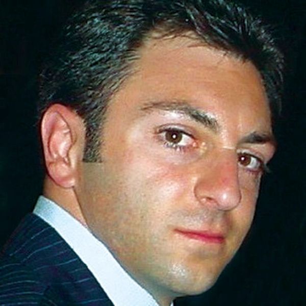 Close-up portrait of a man with dark hair and a serious expression.