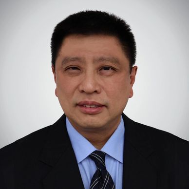 Professional headshot of a man in a suit and tie against a neutral background.