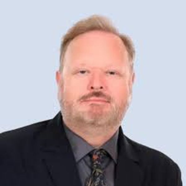 Professional portrait of a man in a suit with a patterned tie.