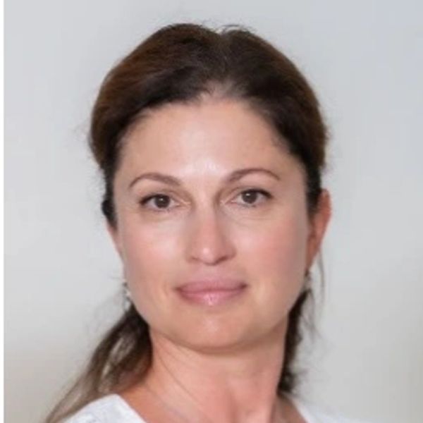 Portrait of a woman with light makeup and brown hair tied back.