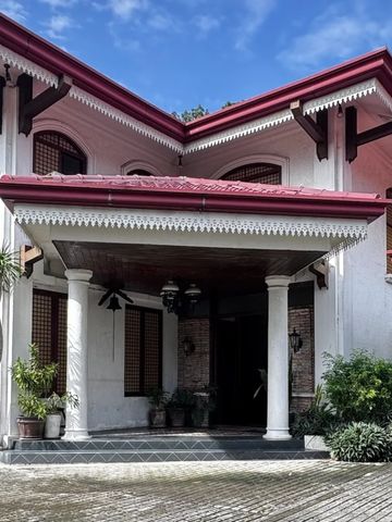 Classic house entrance with red roof and white pillars under a blue sky.