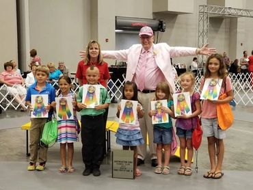 A group of children holding their Pee Wee dog show prize ribbons.