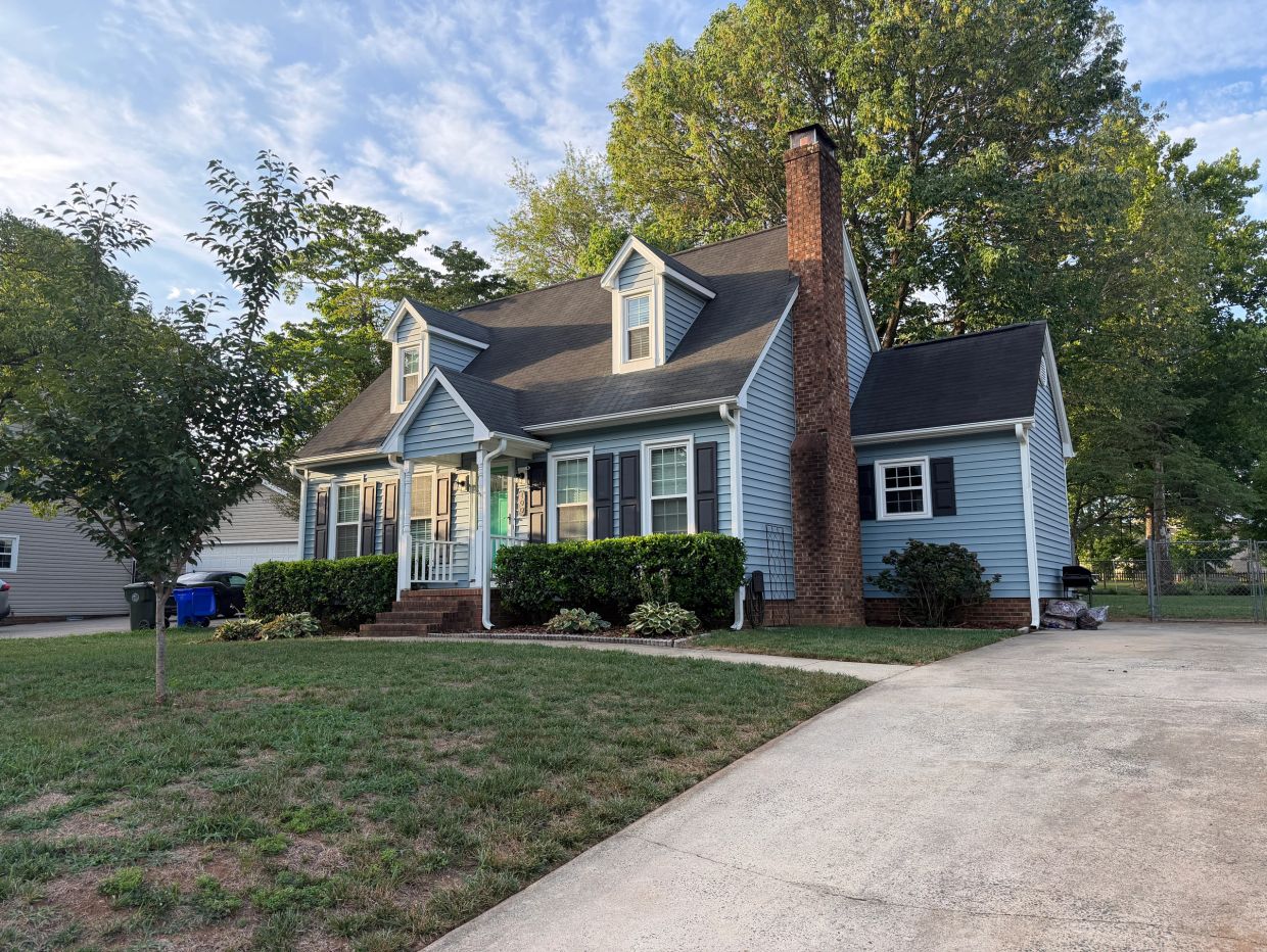Cozy blue house with a brick chimney and dormer windows.