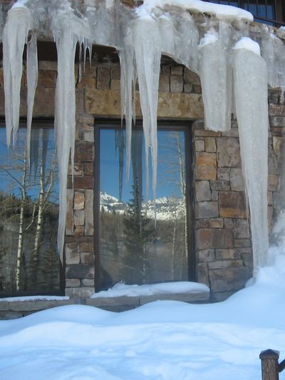 Large icicles hanging over a snowy window.