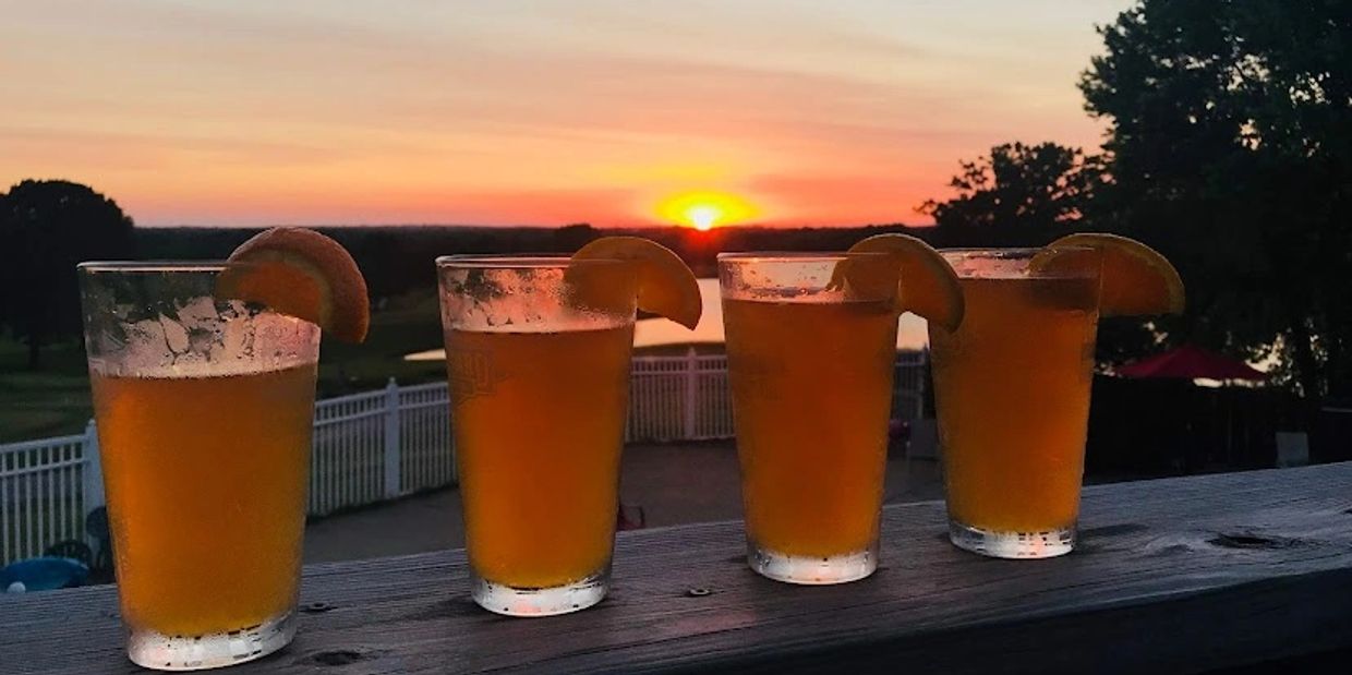 4 pints of beer with orange slices overlooking  the 1st hole at Sandstone Country Club with a sunset