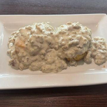 two biscuits covered in sausage gravy on a white plate. 