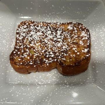 A white plate topped with one slices of Texas toast sprinkled in powdered sugar on top. 