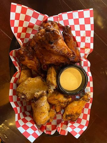 A variety of  bone-in chicken wings covered in a multitude of different sauces in a basket. 