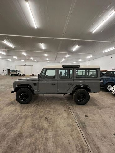 1991 Gray Land Rover Defender 110. 4 doors. Total restoration. All-terrain tires.  Inside showroom.