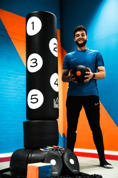 Man in sportswear holding a medicine ball in a gym.