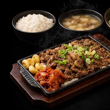 Korean barbecue meal with grilled beef and side dishes.