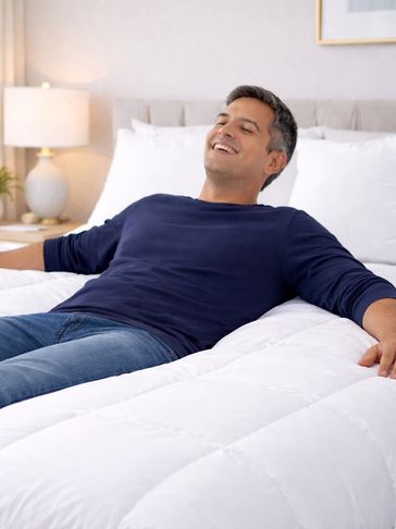 Man happily reclining on a cozy white bed.