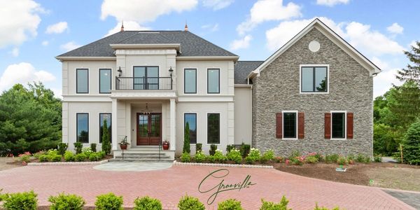 Elegant two-story house with stone and stucco exterior and manicured front yard.