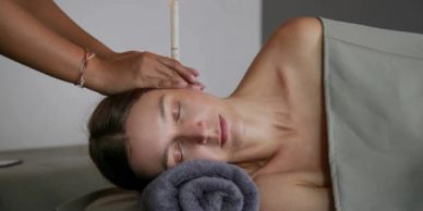 Woman receiving acupuncture on her head while lying down.