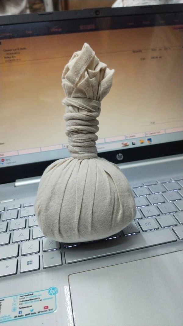 A cloth-wrapped herbal compress ball on a laptop keyboard.