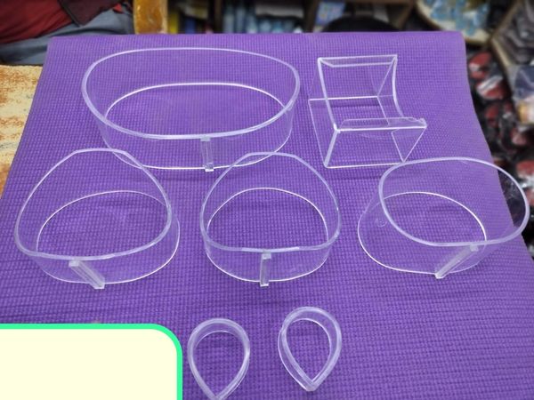 Transparent plastic molds of various shapes on a purple mat.