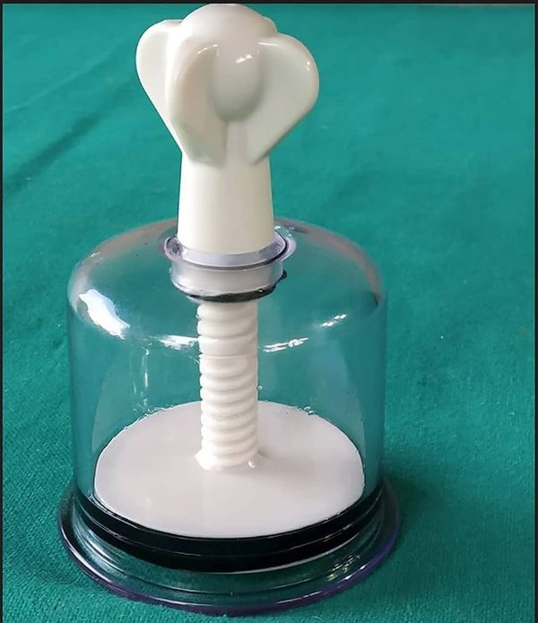 White plastic suction pump with a clear dome on a green surface.