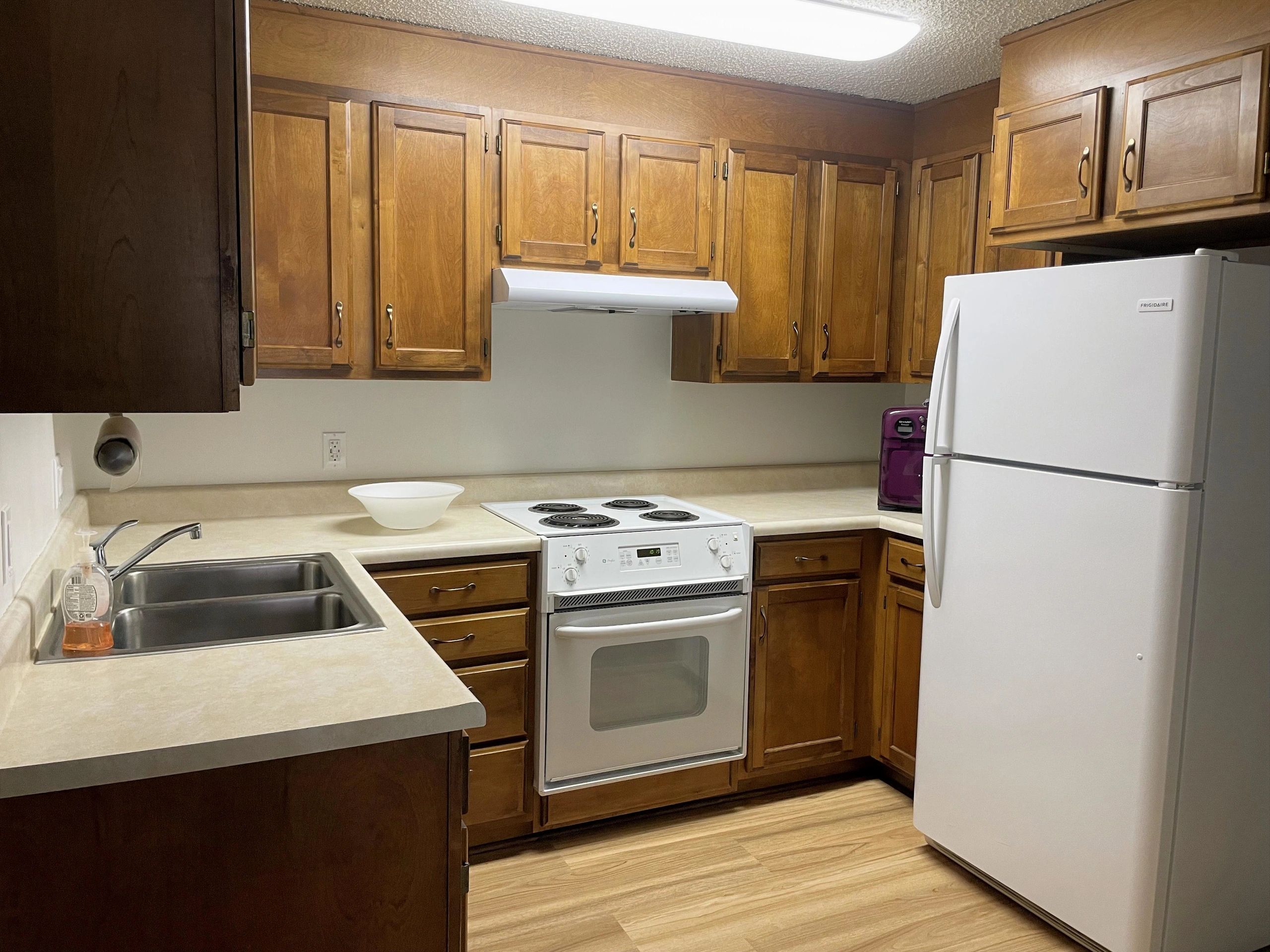 Cozy kitchen with wooden cabinets and white appliances.