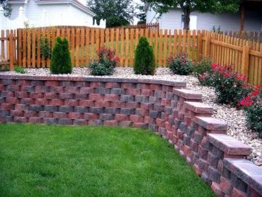 Backyard garden with a brick retaining wall and flowers.