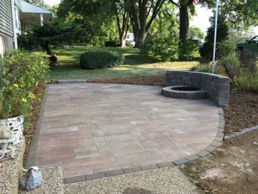 A newly paved backyard patio with a circular fire pit area.
