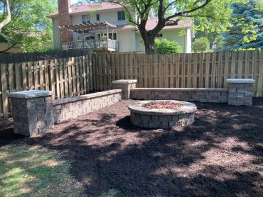 Backyard fire pit with stone benches and fencing.