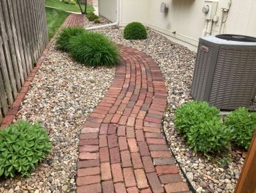 A curved brick pathway surrounded by rocks and plants.
