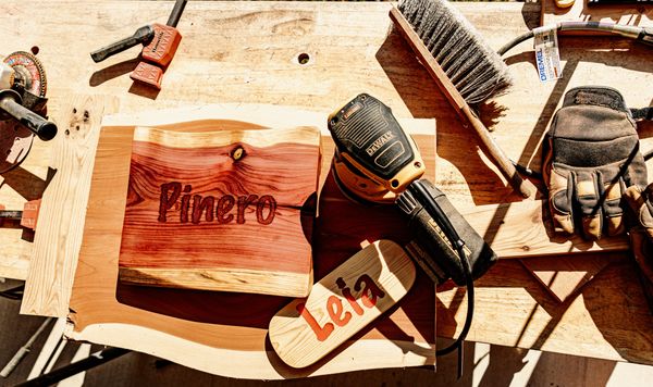 A woodworking setup with personalized wooden plaques and tools on a workbench.