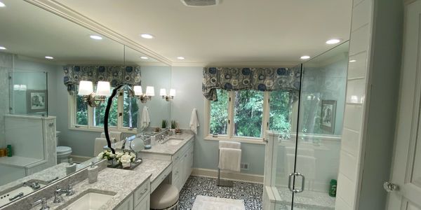 Elegant bathroom with patterned tile floor, double sinks, and glass shower.