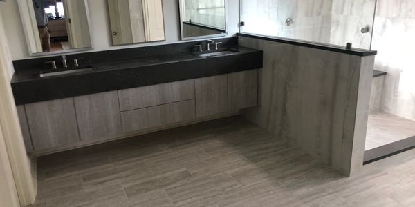 Modern bathroom with dual sinks, large mirrors, and a glass-enclosed shower area.