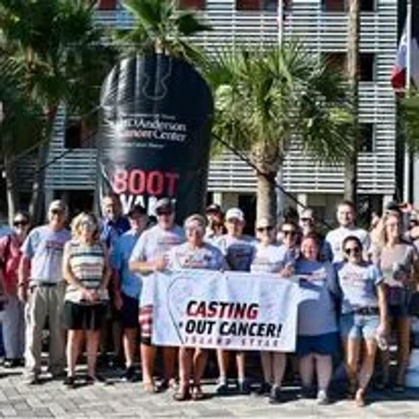 Group holding a banner for cancer awareness at an outdoor event.