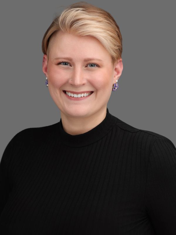 Smiling woman with short blonde hair in a black top.