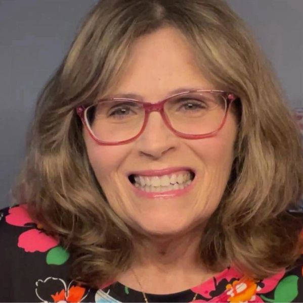 Smiling woman with glasses and floral top.