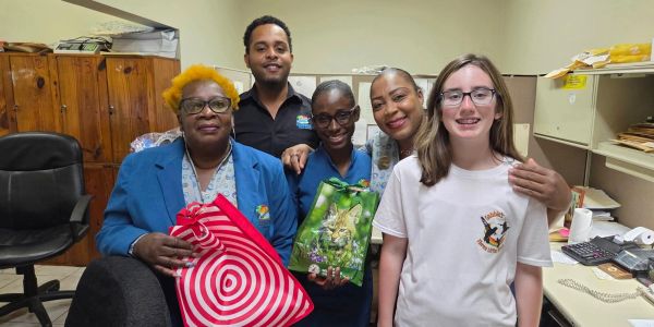 A diverse group of five people smiling and holding gift bags in an office.