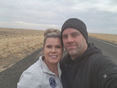 Couple takes selfie on a deserted road with an overcast sky.