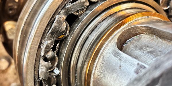 Close-up of a heavily damaged ball bearing with visible wear and corrosion.