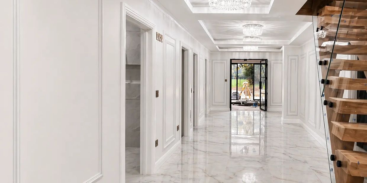 Bright modern hallway with marble floors and wooden staircase.