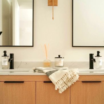 Renovated bathroom with a wood vanity, dual mirrors, black fixtures and modern lighting.