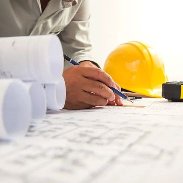 Contractor reviewing building plans with a hard hat and measuring tape for a commercial project.