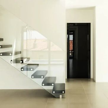 Modern renovated home interior with floating stairs, glass railing and bright open living space.
