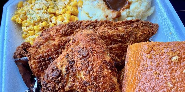 Two-piece chicken entree with corn and mashed potatoes and a square of cornbread