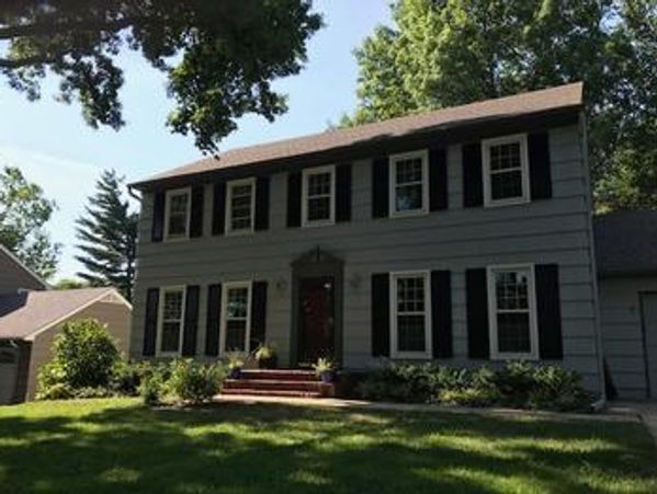Two-story gray house with black shutters and a welcoming front porch.