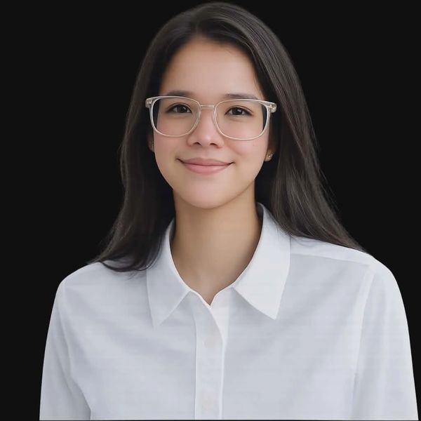 A young woman with glasses smiles warmly against a black background.